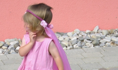 Mädchen in rosa Kleid und rosa Stirnband